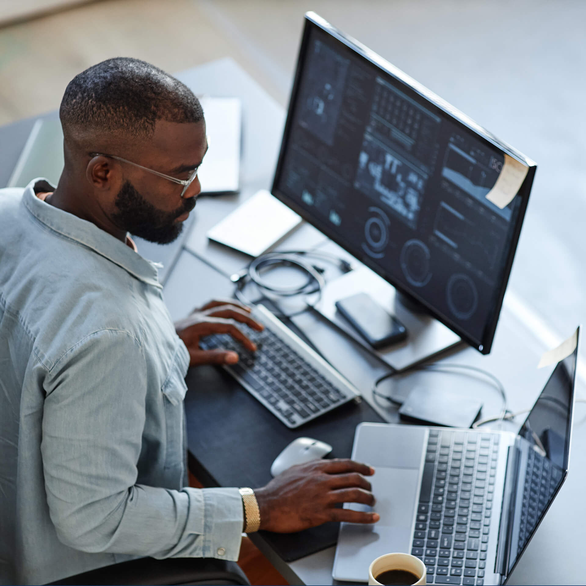 Minimal high angle view at African American software developer working with computers and data systems in office