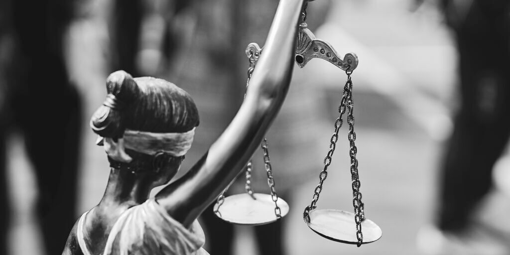 Rear view of themis statue with balance scales in black and white